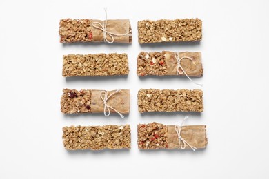 Different tasty granola bars on white background, flat lay