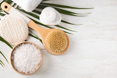 Photo of White sea salt and supplies for spa scrubbing procedure on wooden table, flat lay