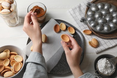 Woman making delicious walnut shaped cookies at white wooden table, top view