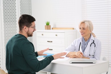 Doctor consulting patient at white table in clinic
