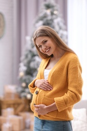 Photo of Young pregnant woman in room decorated for Christmas