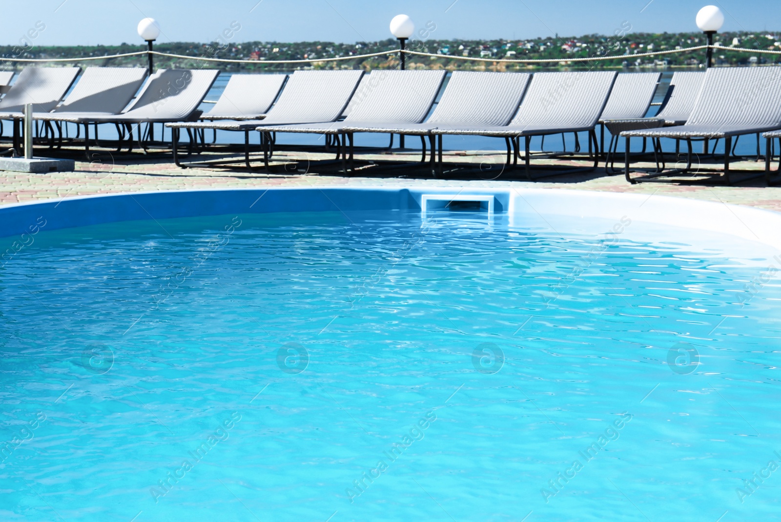 Photo of Swimming pool with clean blue water and lounge chairs outdoors