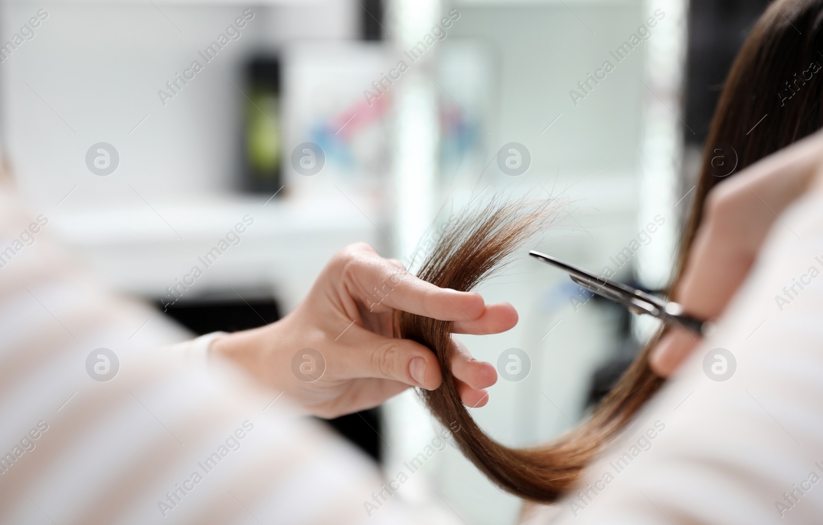 Photo of Hairdresser making stylish haircut with professional scissors in salon, closeup