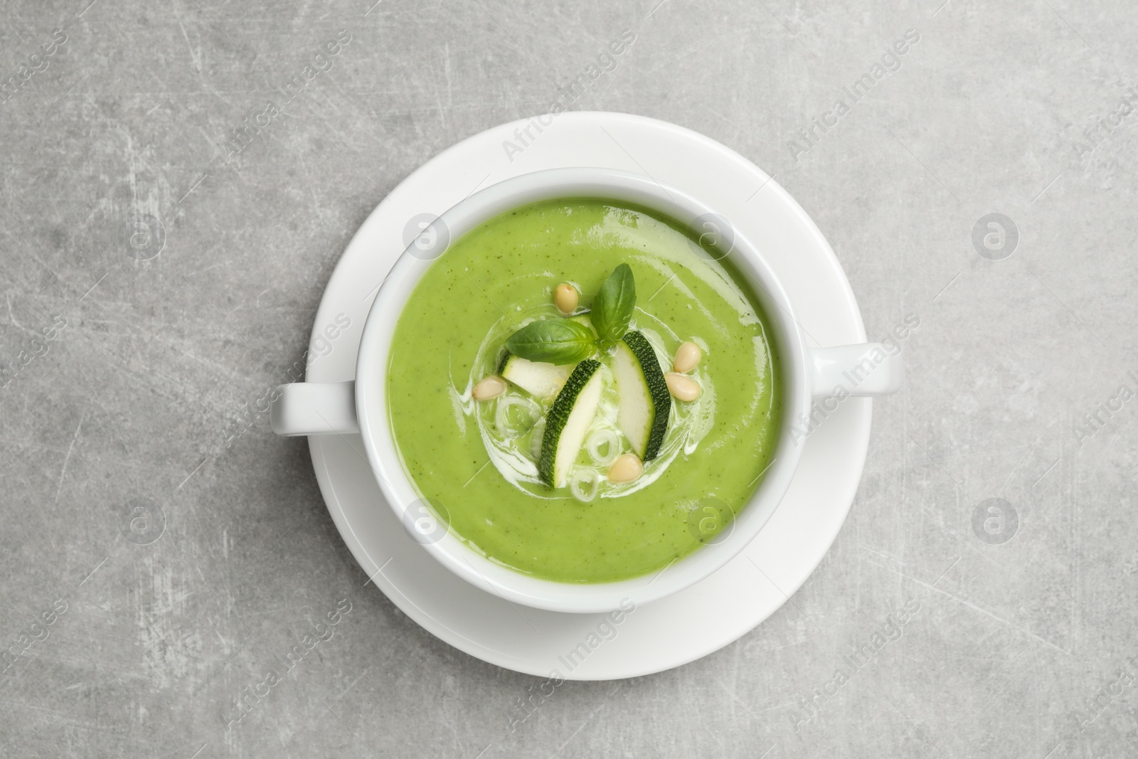 Photo of Tasty homemade zucchini cream soup on grey table, top view