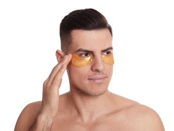 Photo of Man applying golden under eye patch on white background