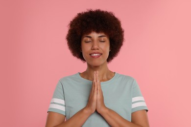 Photo of Woman with clasped hands praying to God on pink background