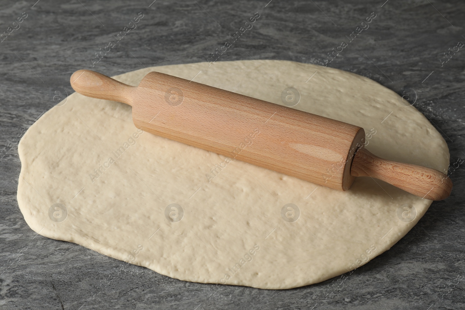 Photo of Raw dough and rolling pin on grey table