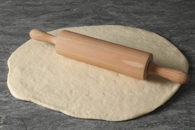 Photo of Raw dough and rolling pin on grey table