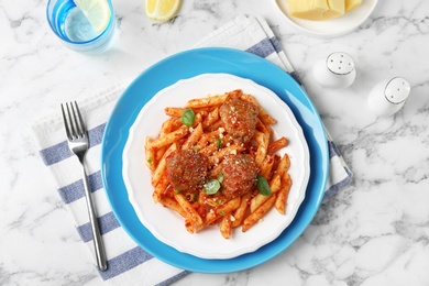 Delicious pasta with meatballs and tomato sauce on light background, top view