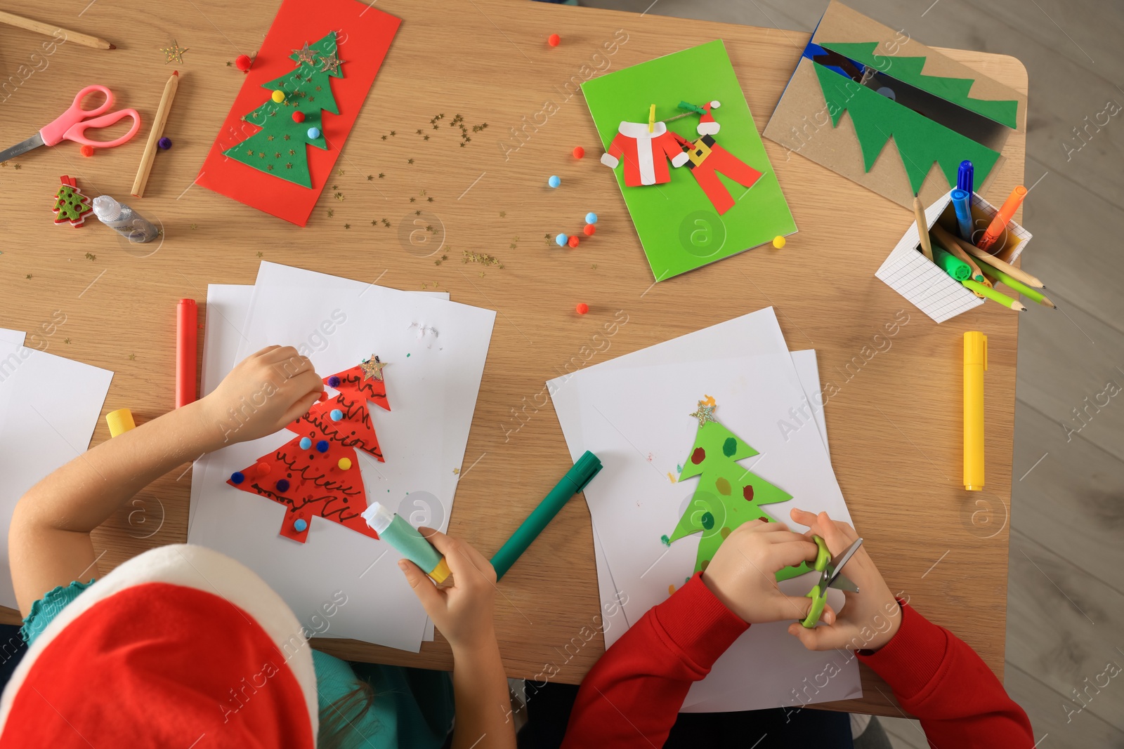 Photo of Little children making beautiful Christmas greeting cards at table, top view