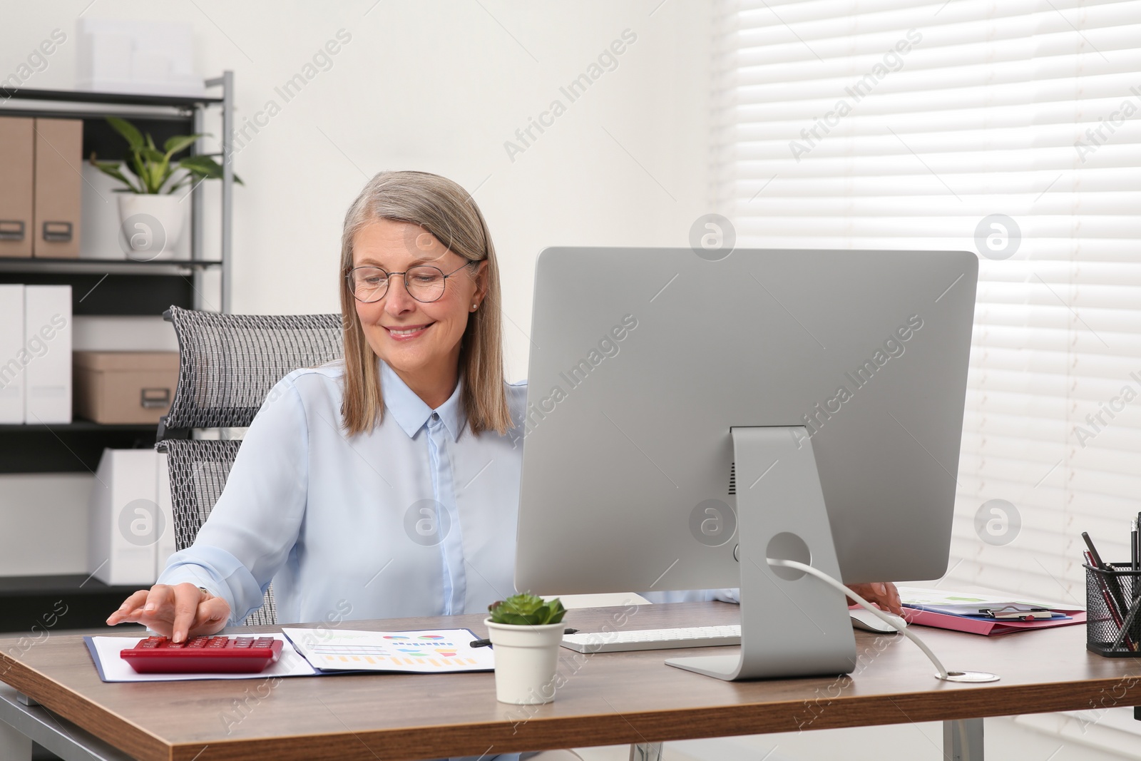 Photo of Senior accountant working at wooden desk in office