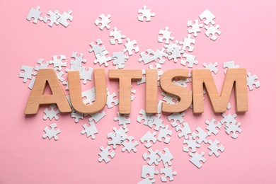 Photo of Word "Autism" and puzzle pieces on color background