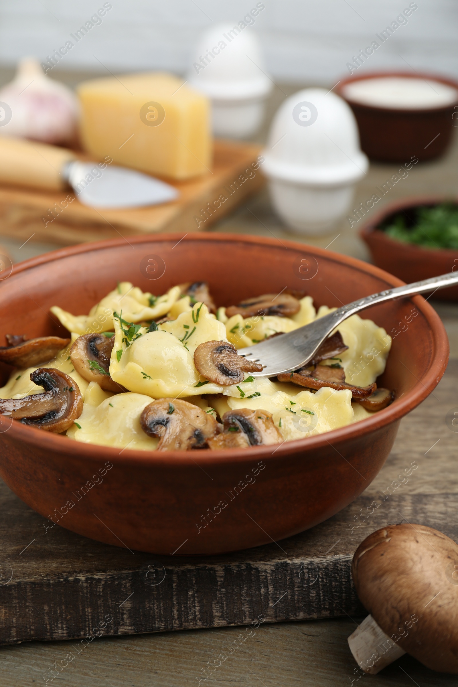 Photo of Delicious ravioli with mushrooms and fork on wooden table, closeup