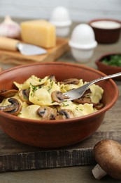 Delicious ravioli with mushrooms and fork on wooden table, closeup