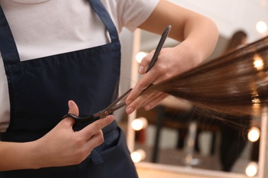 Photo of Stylist cutting hair of client in professional salon, closeup