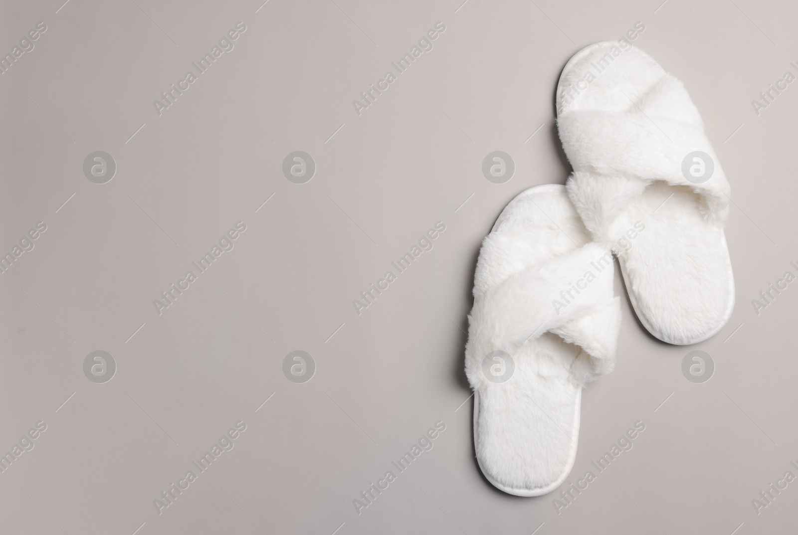 Photo of Pair of soft fluffy slippers on light grey background, top view. Space for text