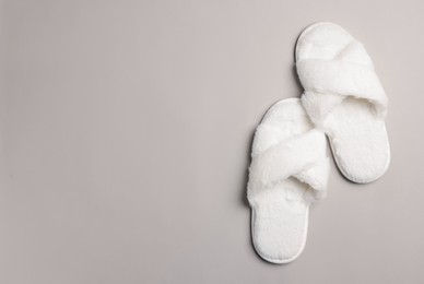 Photo of Pair of soft fluffy slippers on light grey background, top view. Space for text