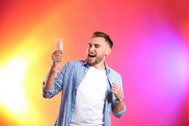 Portrait of happy man with champagne in glass on color background