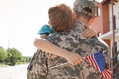 Photo of American soldier hugging with his son outdoors. Military service