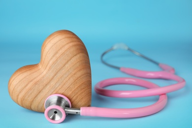 Photo of Stethoscope with wooden heart on blue background, closeup. Space for text