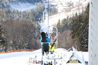 Photo of Couple using chairlift at mountain ski resort. Winter vacation