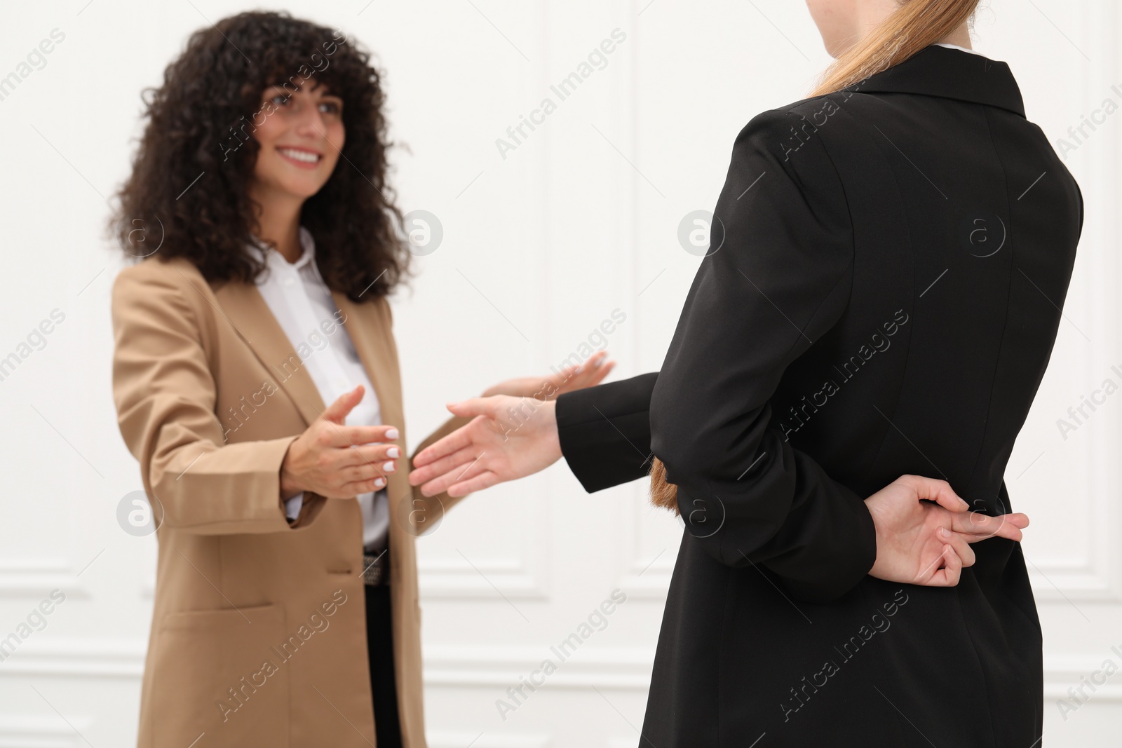 Photo of Employee crossing fingers behind her back while meeting with boss in office, closeup