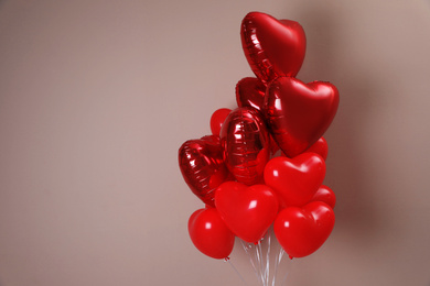 Photo of Bunch of heart shaped balloons on beige background, space for text. Valentine's day celebration