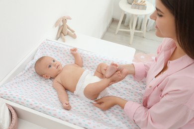 Photo of Mother changing her baby's diaper on table at home