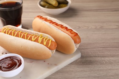 Photo of Tasty hot dogs with mustard and ketchup on wooden table. Space for text