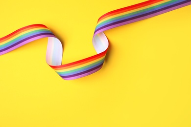 Photo of Bright rainbow ribbon on color background, top view with space for text. Symbol of gay community