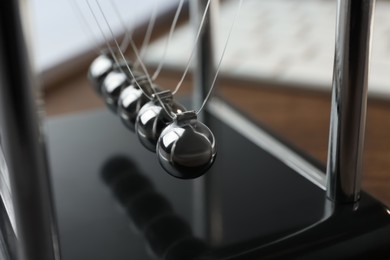 Photo of Newton's cradle on table, closeup. Physics law of energy conservation