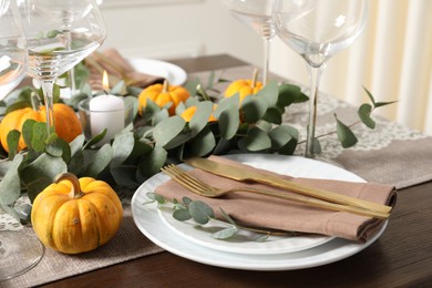 Beautiful autumn table setting. Plates, cutlery, glasses, pumpkins and floral decor