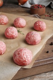 Photo of Many fresh raw meatballs on wooden board