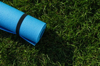 Photo of Bright exercise mat on fresh green grass outdoors, top view. Space for text