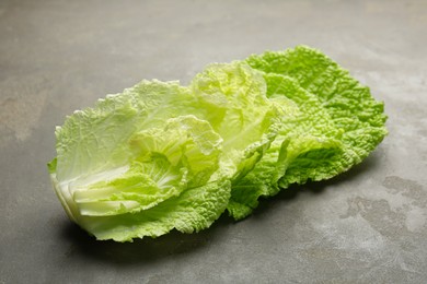 Photo of Fresh Chinese cabbage leaves on gray textured table, closeup
