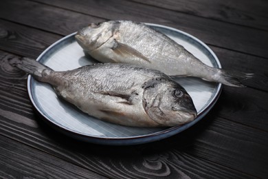 Photo of Fresh raw dorado fish on black wooden table, closeup