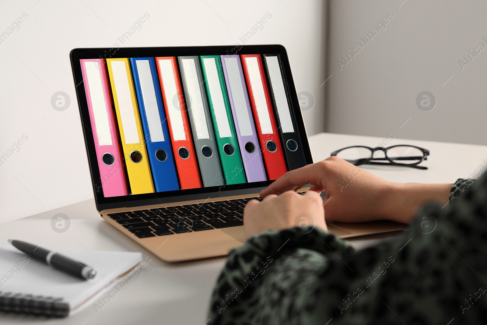 Image of Store and organize data. Woman working with information indoors, closeup. Modern laptop with hardcover office folders on screen.