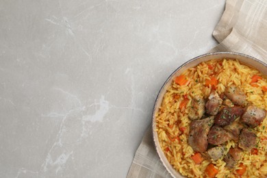 Photo of Delicious pilaf with meat on light grey marble table, top view. Space for text