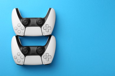 Photo of Wireless game controllers on light blue background, flat lay. Space for text