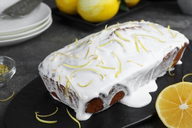 Photo of Tasty lemon cake with glaze and citrus fruits on table, closeup