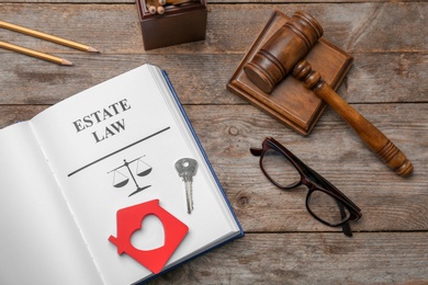 Photo of Flat lay composition with book, gavel and house key on wooden background. Estate law concept
