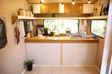 Photo of Stylish kitchen interior with different jars and utensils in modern trailer. Camping vacation