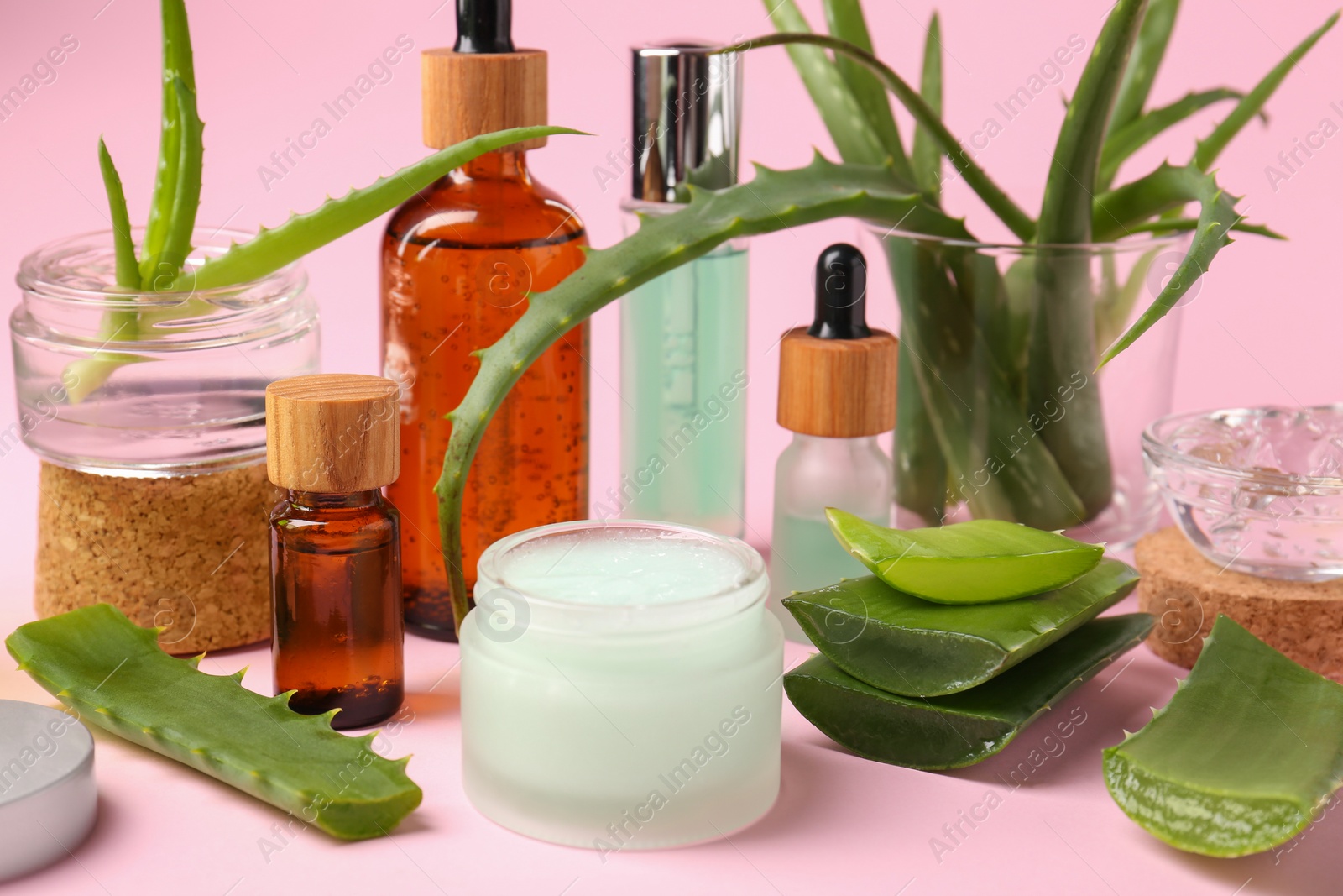 Photo of Cosmetic products and cut aloe on pink background