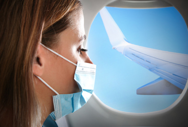 Traveling by airplane during coronavirus pandemic. Woman with face mask near porthole