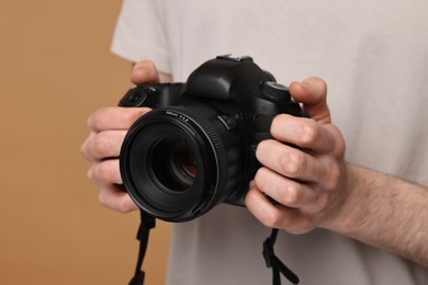 Photo of Photographer holding camera on beige background, closeup