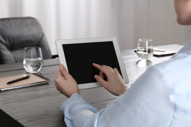 Photo of Woman using tablet at desk in office, closeup. Space for design
