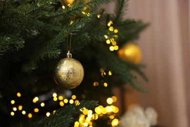 Photo of Christmas ball hanging on fir tree branch indoors, closeup. Space for text