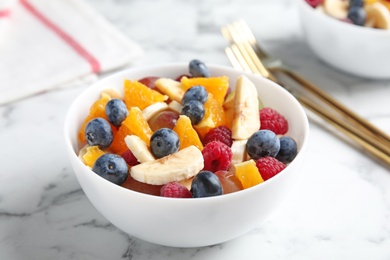 Photo of Fresh tasty fruit salad on white marble table