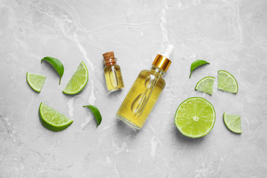 Photo of Flat lay composition with lime essential oil on light grey marble background