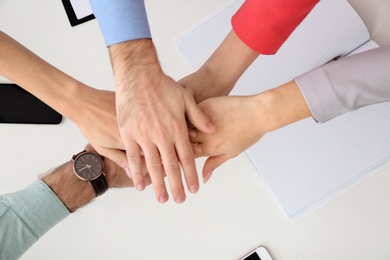 Photo of Young people holding hands together over table, top view. Team victory concept